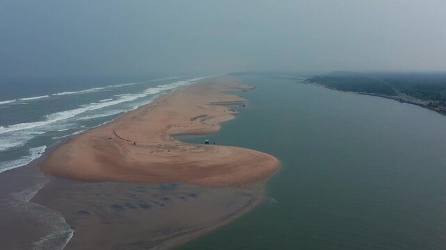 erial view highlights Chandrabhaga Beach's dramatic sandbar at river mouth where orange sands meet crashing waves and lush green forested shores.