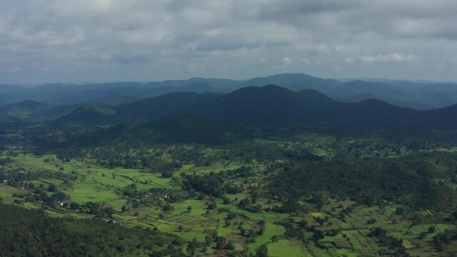 Aerial sweep of Daringbadi's rolling green hills, terraced fields, and forested valleys in Odisha's Kashmir-like landscape under partly cloudy skies.