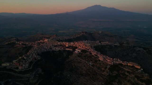 Aerial travel footage presenting Centuripe as a peaceful Sicilian hill town at dusk. Drone footage approaching Centuripe as the landscape transitions from light to shadow.