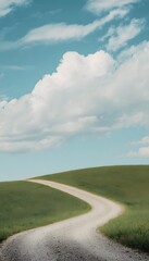Obraz premium Peaceful country road climbs through green hills under a bright expansive blue sky landscape
