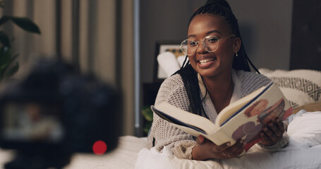 Woman, influencer and reading book with smile for content creation, camera or literature for children. African person, happy and online tutorial on social media, story or recording on bed at house
