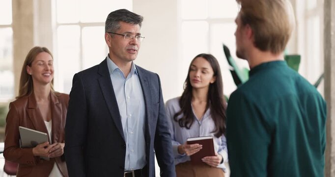 Male manager and client or applicant shaking hands during collaborative group meeting in office, representing trust in business, partnership, successful negotiation, agreement. Staffing, employment
