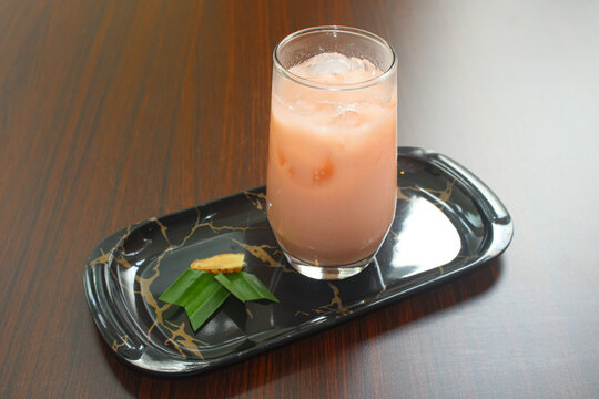 Cold pink guava milk with ice on black marble tray