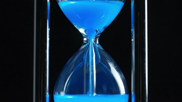 Blue sand timer counting down time with black background.