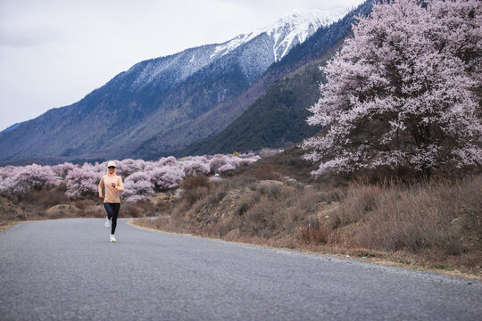 Woman running in peach flowers blooming tibet, China