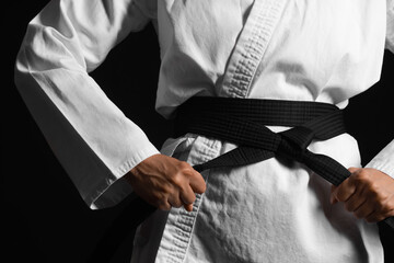 Young woman practicing karate on black background, closeup © Pixel-Shot