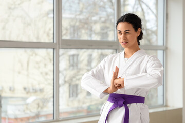 Obraz premium Young African-American woman with purple belt practicing karate in dojo