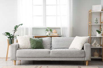 Fototapeta premium Interior of light living room with grey sofa and window