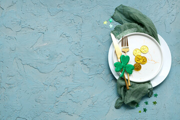 Table setting for St. Patrick's Day celebration with decorative clover and coins on blue grunge...