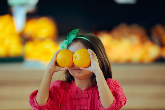 Funny Girl Holds Oranges in Front of Her Eyes in the Supermarket. Child makes grocery shopping fun with a silly pair of citrus eyes 