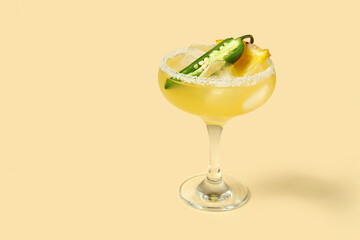 Glass of tasty margarita cocktail with jalapeno and pineapple on beige background