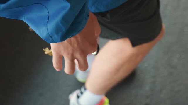 coach holding whistle and keys closeup of hand on wet sideline wearing blue jacket and black shorts sneaker visible preparing to signal during rainy football practice moody drizzle tense focus