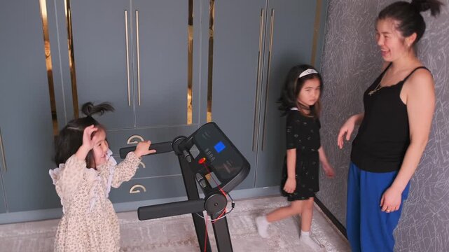 child safely exercising, young asian child and sibling engage in treadmill exercise safely at home, child and sibling from asia perform safe treadmill exercise together with gentle supervision at home