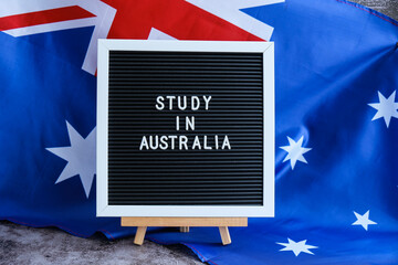 Message STUDY IN AUSTRALIA on background of Australian flag made from silk. Australia national flag with concept of tourism and traveling. Welcoming students opportunities scholarship programs