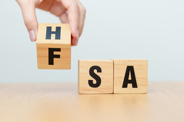 hand change wooden block from FSA to HSA. Flexible Spending Account and Health Savings Account,...