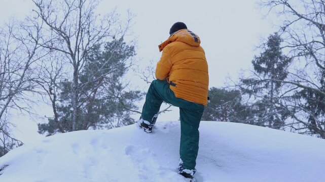 A man travels in the mountains in winter. Traveler raising arms victoriously. The concept of travel and active lifestyle. 4K