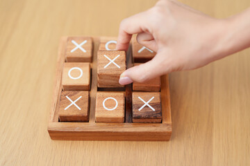Hand holding and playing wooden block of tic tac toe game. A completed game of noughts and crosses...