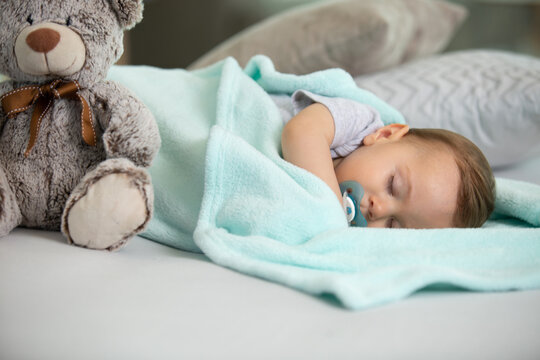 baby asleep with a pacifier and a teddy-bear