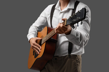 Naklejka premium Young man playing guitar on dark background