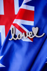 Fototapeta premium Wooden word LOVE on background of National symbol of Australia flag background. Copy space for your text. Concept of National day Independence