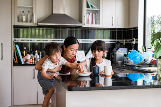 Mum gets her children snacks in a bright kitchen, promoting family bonding and fun