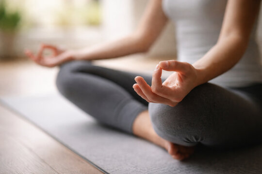 Woman meditating in a peaceful lotus pose on a yoga mat, practicing mindfulness and inner calm.