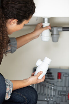 rear view of woman fitting syphon to waste water pipe