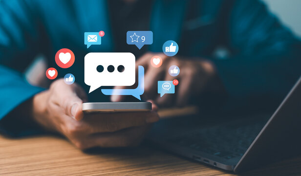 A user holds a smartphone, engaging with dynamic social media notifications floating above the screen, like, comment, and heart icons. digital marketing concept network engagement mobile technology. - Powered by Adobe