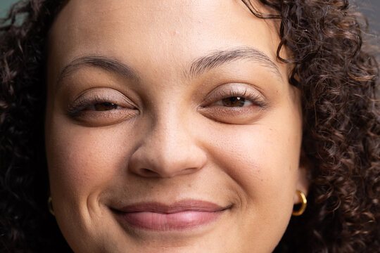 African American woman smiling softly while posing at studio wearing gold hoop earrings