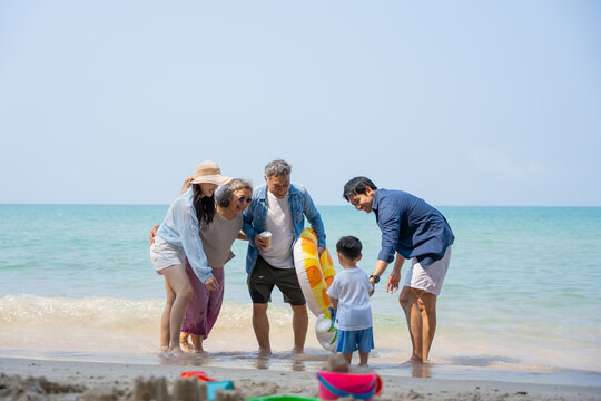 Multi-generational Asian family enjoying summer beach vacation together. Grandparents, parents, and child bonding by the sea, joyful outdoor. family, beach, vacation, summer, multi-generational.