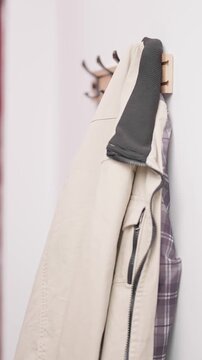 Person hand hang stylish beige jacket on hook