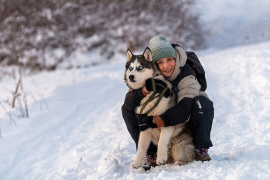 woman hugs her husky dog during a winter walk.