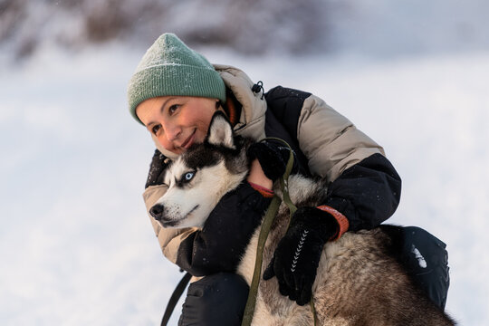 woman hugs her husky dog during a winter walk.