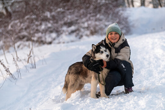 woman hugs her husky dog during a winter walk.