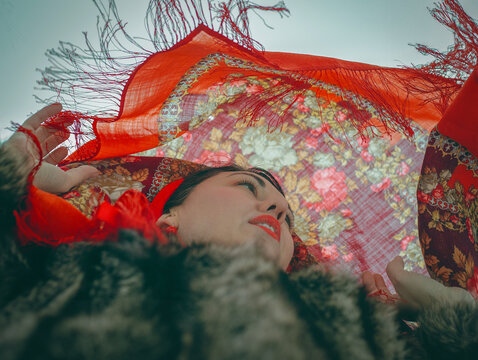 A woman in a fur coat and a red scarf flying from above