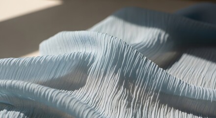 Soft blue fabric with delicate pleats, illuminated by natural sunlight and shadows.