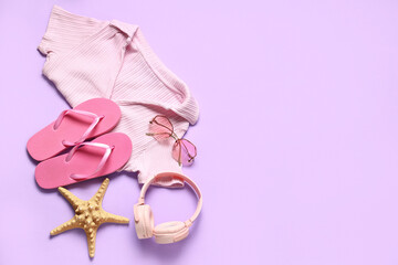 Female summer clothes with flip flops, headphones and starfish on lilac background