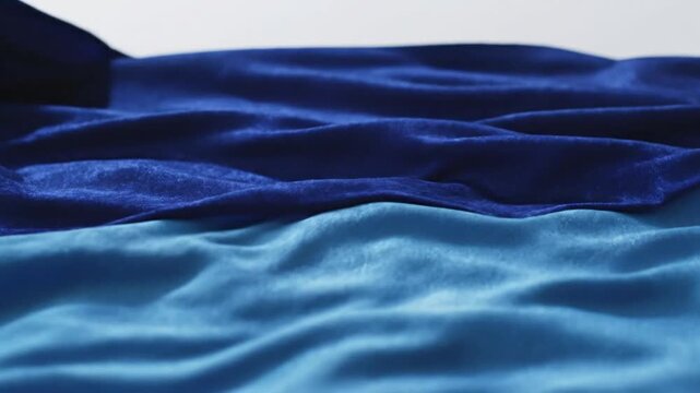A close-up view of blue fabric with creases on a white background