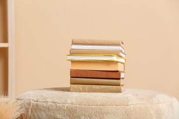 Stack of books on pouf near color wall