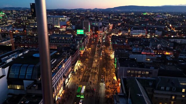 aerial landscape drone shot quickly panning over O'Connell street in Dublin Ireland city with spire landmark in winter nighttime with illuminated streets and Irish architecture cityscape