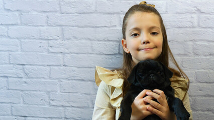 Little Girl Hugging and Playing with Black Pug Puppy, Child Love and Care Concept with Copy Space