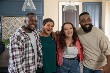 Diverse friends standing in kitchen beside island with mosaic backsplash and houseplant