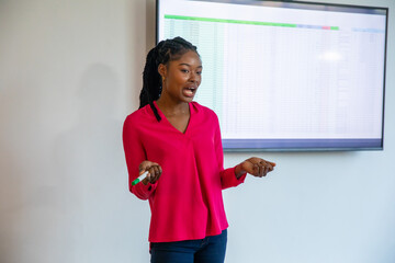 African american woman in blouse presenting spreadsheet on screen in office holding marker