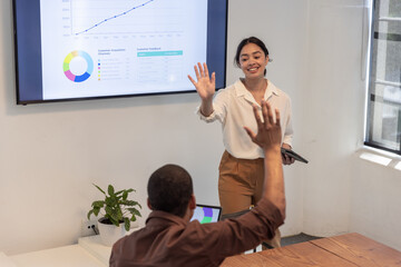 Diverse coworkers analyzing data on display at conference room, tablet, laptop, plant, copy space