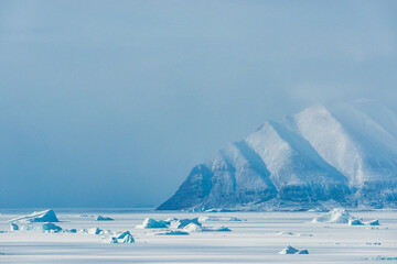 Snowy mountains and frozen icebergs near Qaanaaq in Greenland during winter season