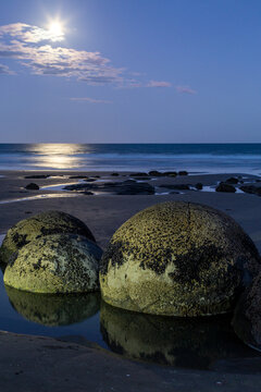 Moeraki boulders on beach at dusk  with bright moon and starburst.
