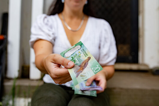 Close-up of a woman's hands holding New Zealand currency