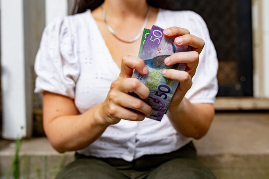 Close-up of a woman's hands holding New Zealand currency