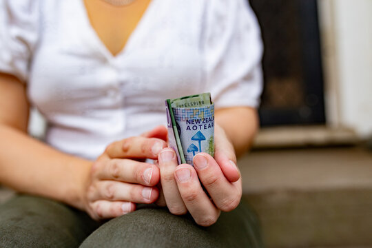Close-up of a woman's hands holding New Zealand currency