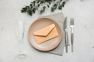 Beautiful table setting with envelope and eucalyptus branches on grey background